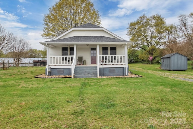 exterior space featuring an outbuilding, a front yard, a storage unit, roof with shingles, and covered porch