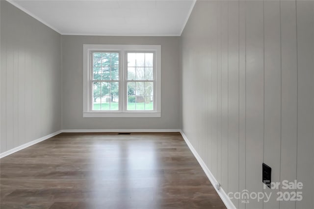 spare room with baseboards, dark wood-style flooring, and crown molding