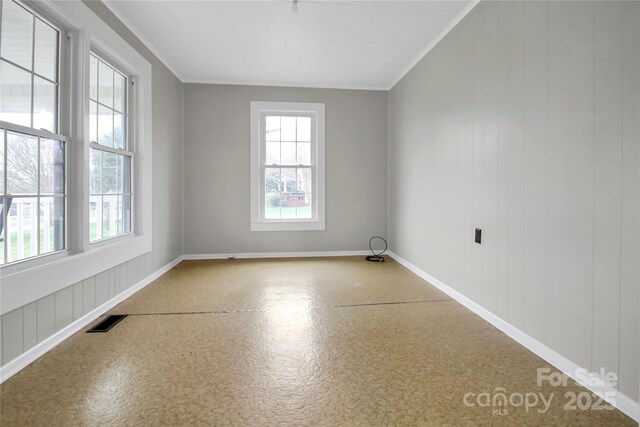 spare room featuring baseboards, ornamental molding, and visible vents