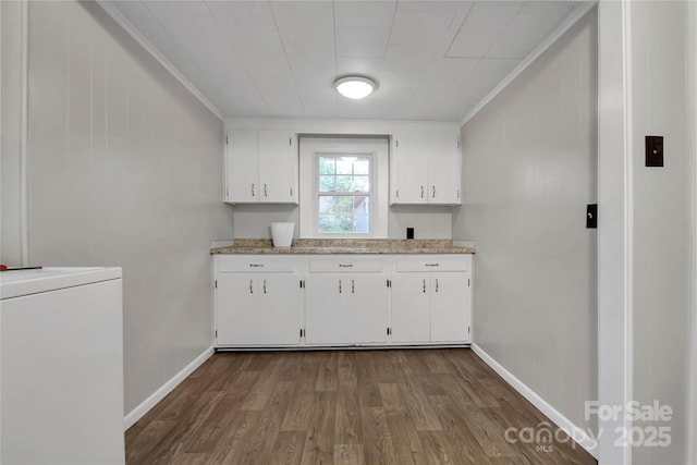 clothes washing area with dark wood finished floors, baseboards, ornamental molding, and washer / dryer
