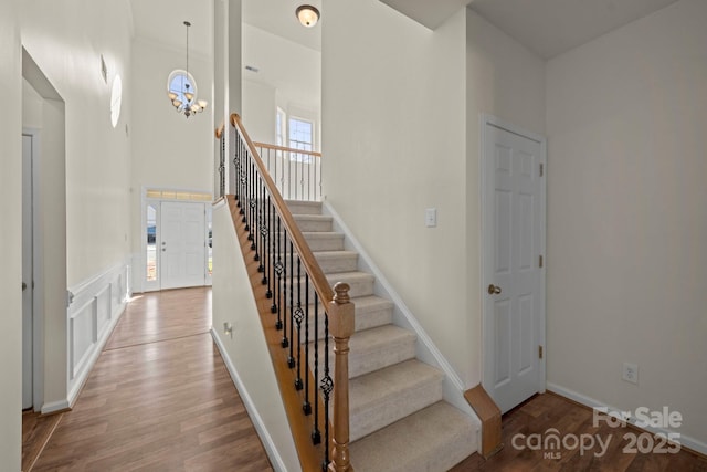 15814 Herring Gull Way, Charlotte, NC 28278 - stairway featuring a decorative wall, a towering ceiling, wood finished floors, and an inviting chandelier