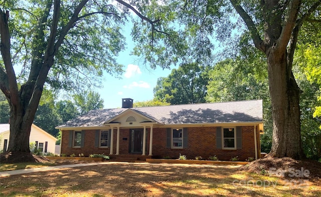 ranch-style home featuring a chimney and brick siding