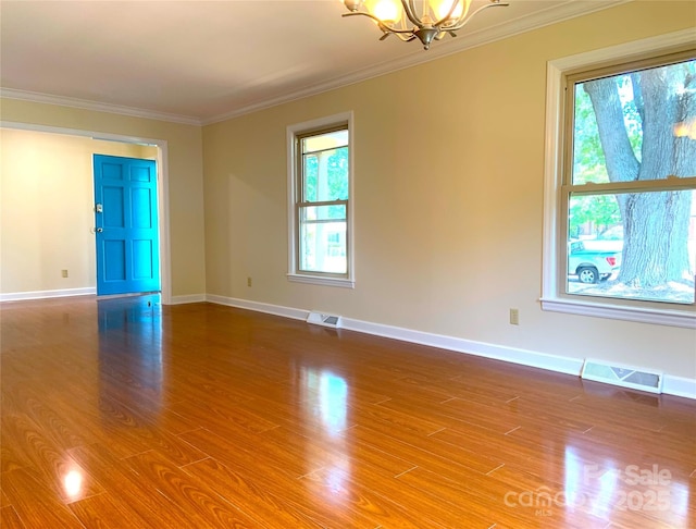 unfurnished room with a notable chandelier, wood finished floors, crown molding, and visible vents