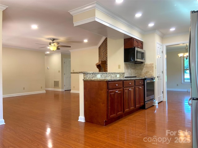 kitchen with stainless steel appliances, visible vents, backsplash, ceiling fan with notable chandelier, and wood finished floors
