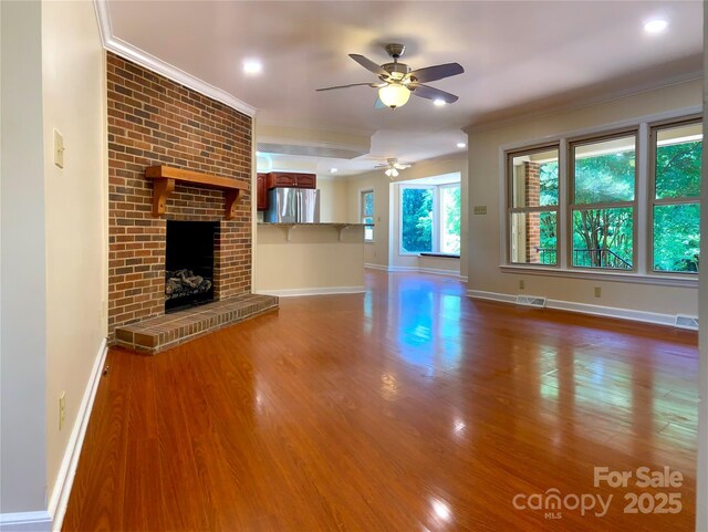 unfurnished living room with baseboards, visible vents, wood finished floors, ceiling fan, and ornamental molding
