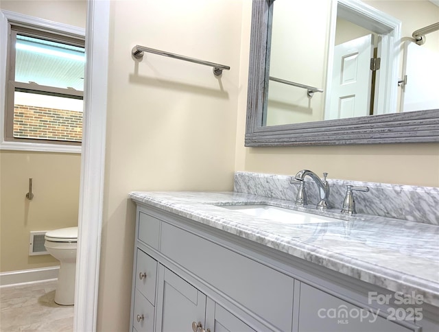 bathroom featuring baseboards, visible vents, toilet, and vanity
