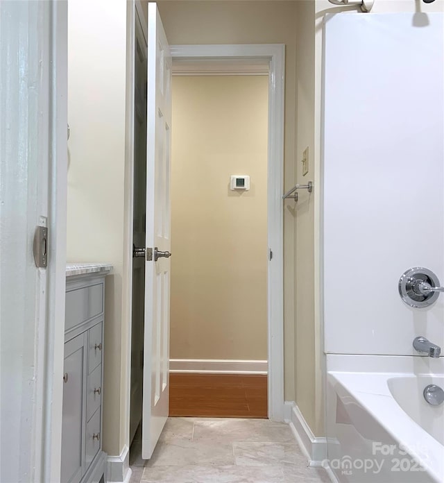 bathroom featuring shower / washtub combination, baseboards, and vanity
