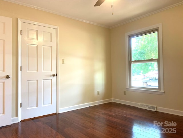 empty room with a ceiling fan, dark wood finished floors, baseboards, ornamental molding, and visible vents