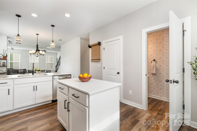 kitchen featuring dishwasher, dark wood finished floors, open floor plan, a sink, and hanging light fixtures