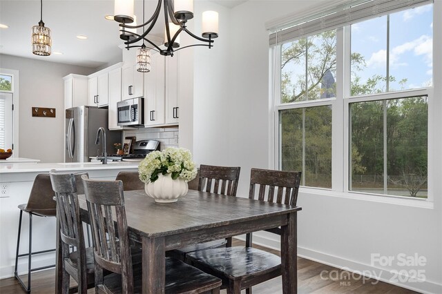 dining room featuring plenty of natural light, dark wood finished floors, a chandelier, recessed lighting, and baseboards
