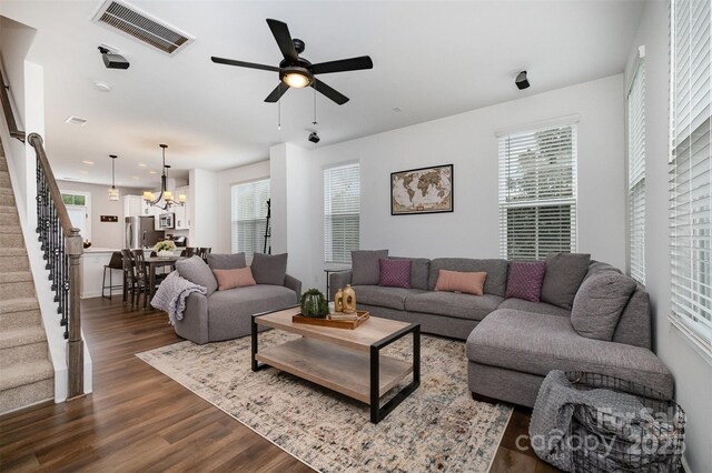 living room with stairway, plenty of natural light, dark wood-style floors, and a chandelier