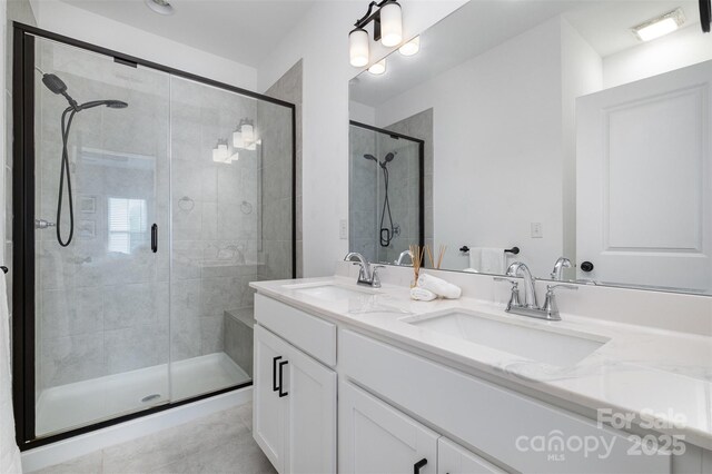 bathroom featuring a shower stall, double vanity, and tile patterned floors