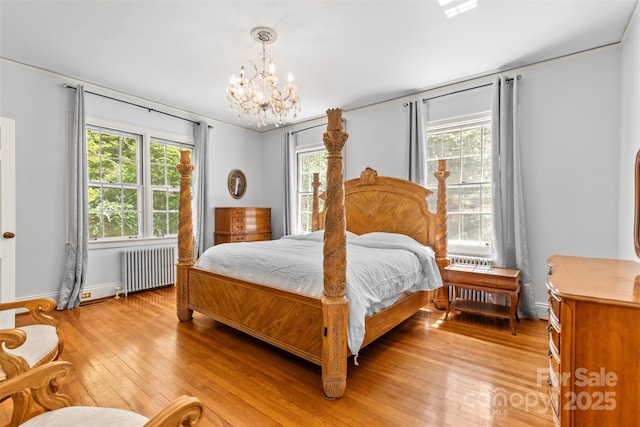 1233 General Hoke Dr, Lincolnton, NC 28092 - bedroom with radiator heating unit, a notable chandelier, multiple windows, and light wood-style flooring