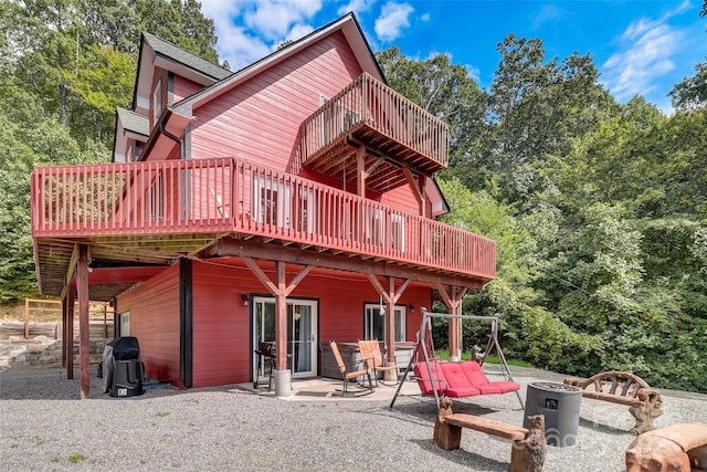 rear view of house with a patio, a deck, and an outdoor fire pit
