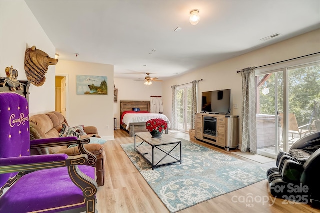 living area featuring plenty of natural light, visible vents, ceiling fan, and wood finished floors