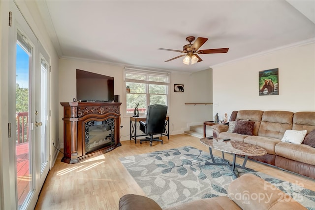 living room featuring a glass covered fireplace, ceiling fan, ornamental molding, and wood finished floors