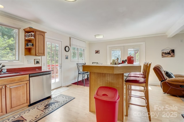 kitchen with light wood finished floors, dishwasher, a kitchen bar, and ornamental molding