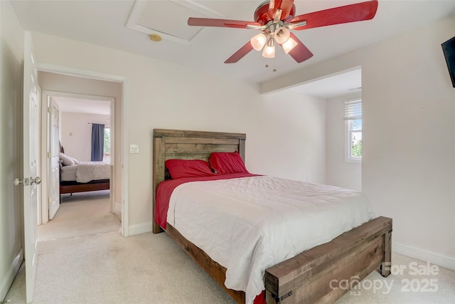 bedroom featuring ceiling fan, attic access, light colored carpet, and baseboards
