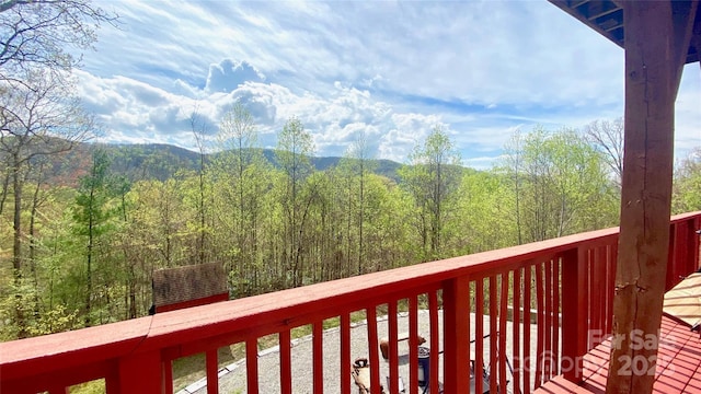balcony featuring a wooded view and a mountain view