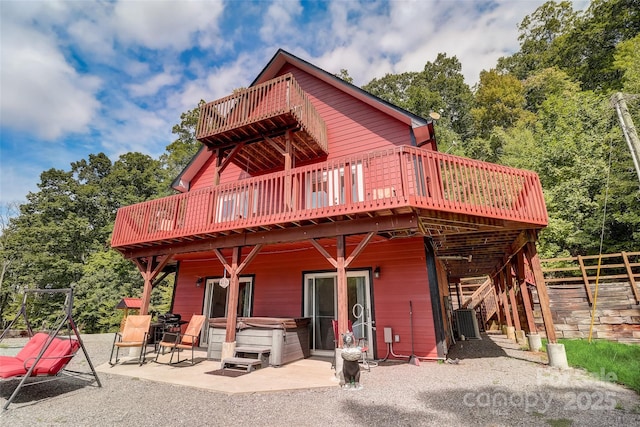 rear view of house with a patio area, central air condition unit, a deck, and a hot tub
