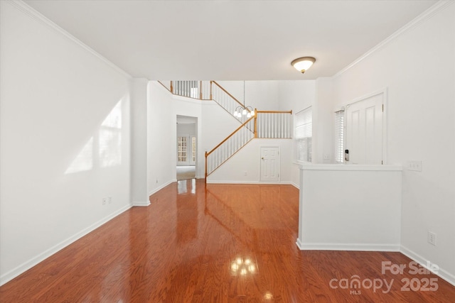 interior space with crown molding, baseboards, wood finished floors, and stairs