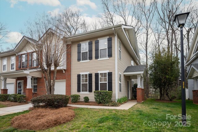 view of property with a garage, a front lawn, and brick siding