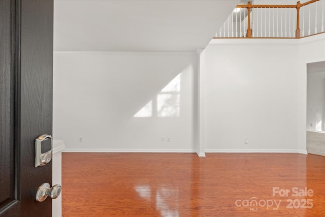 spare room featuring baseboards, ornamental molding, and wood finished floors