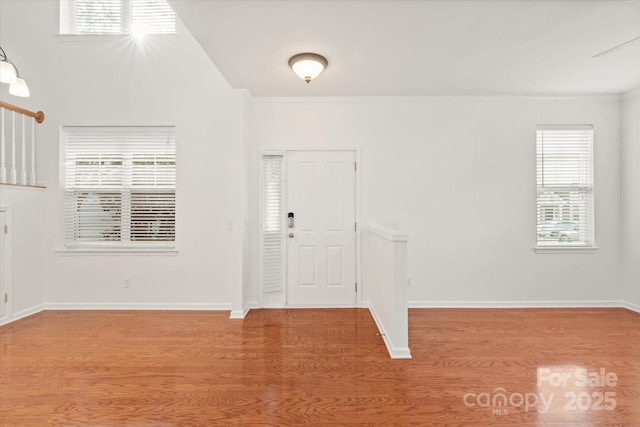 entryway featuring baseboards, ornamental molding, and wood finished floors