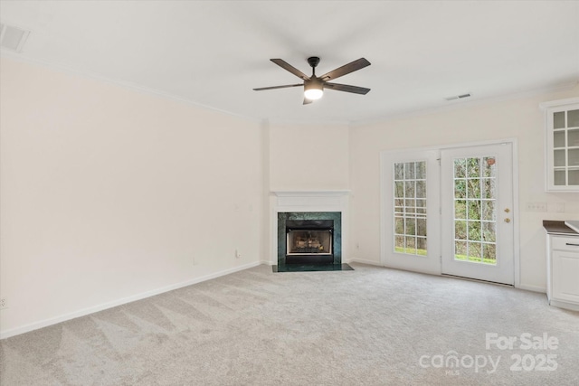 unfurnished living room featuring carpet flooring, a premium fireplace, crown molding, and ceiling fan