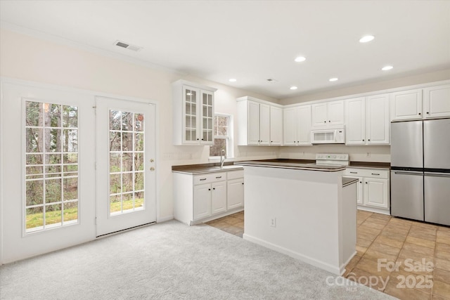 kitchen featuring range, stainless steel refrigerator, white microwave, visible vents, and light colored carpet
