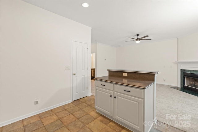 kitchen featuring a fireplace, open floor plan, white cabinetry, dark countertops, and ceiling fan