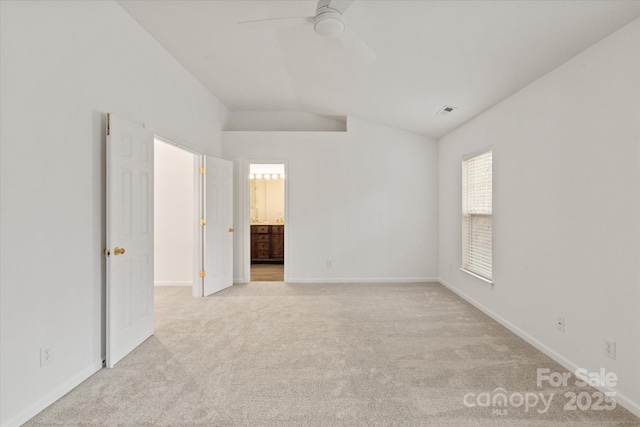 unfurnished bedroom featuring visible vents, baseboards, ensuite bath, carpet flooring, and lofted ceiling