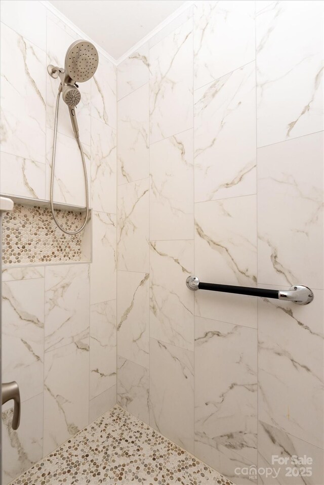 bathroom with crown molding and tiled shower