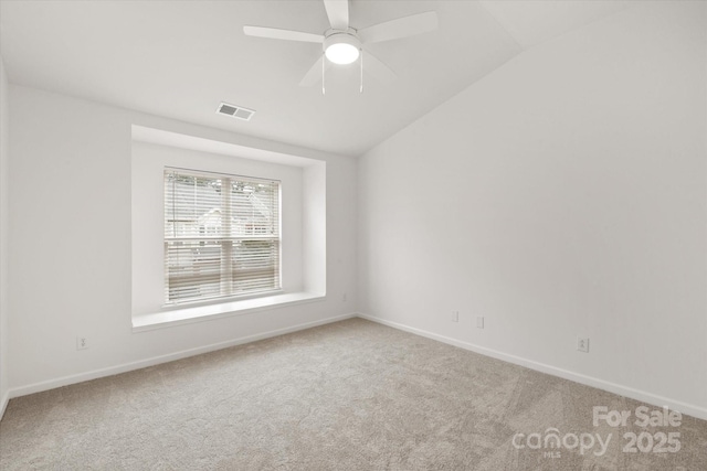 carpeted empty room with ceiling fan, visible vents, baseboards, and lofted ceiling