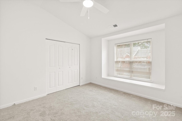 unfurnished bedroom featuring visible vents, vaulted ceiling, carpet floors, and a closet
