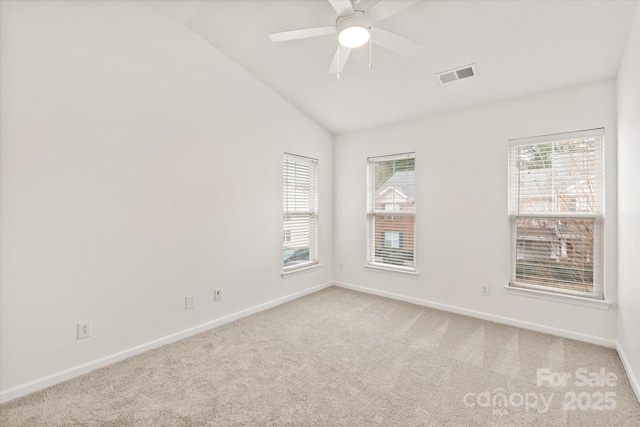 carpeted spare room with a wealth of natural light, visible vents, baseboards, and vaulted ceiling
