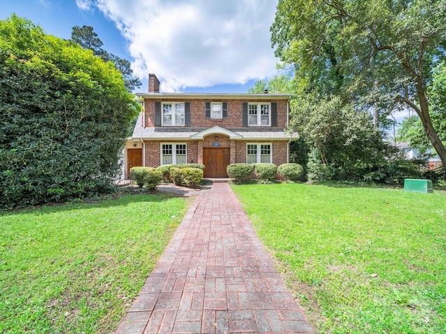 view of front of house featuring brick siding, a chimney, and a front lawn