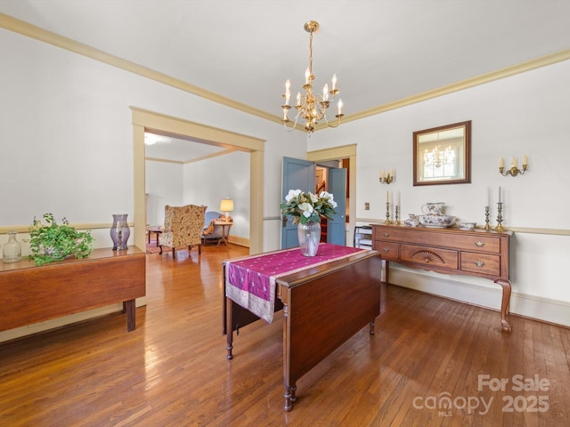 dining area featuring crown molding, baseboards, an inviting chandelier, and hardwood / wood-style floors