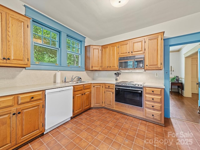 kitchen featuring white dishwasher, a sink, light countertops, gas stove, and tile patterned floors