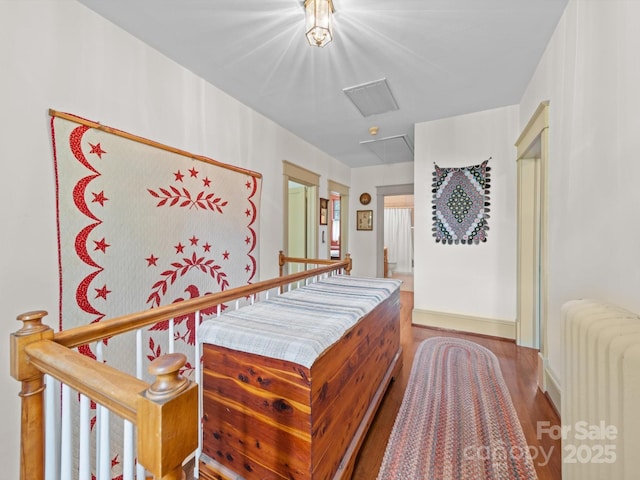 bedroom featuring attic access, radiator, and wood finished floors