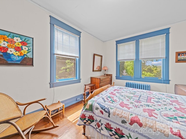 bedroom featuring radiator, wood finished floors, and baseboards