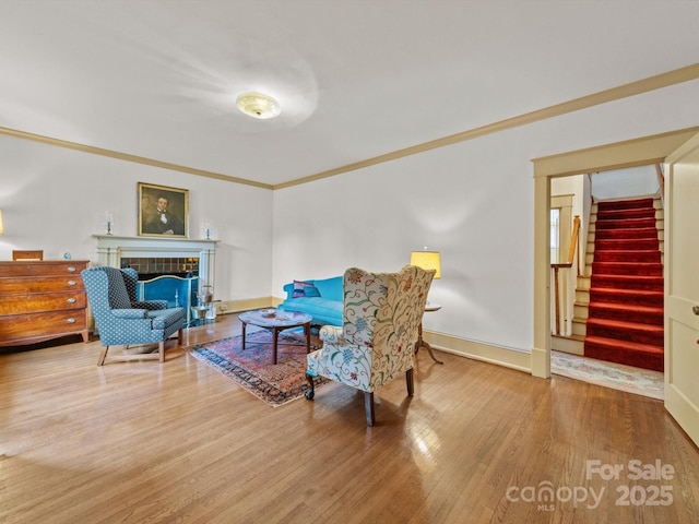 sitting room featuring ornamental molding, stairway, wood finished floors, a tile fireplace, and baseboards