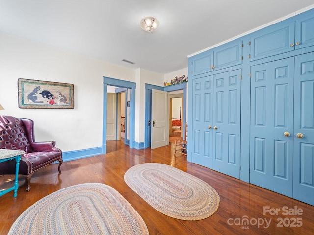 living area featuring visible vents, baseboards, and wood finished floors