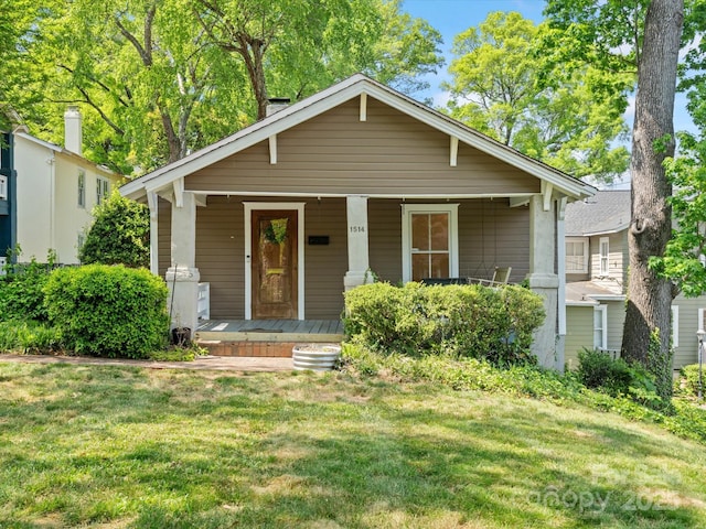 bungalow-style home featuring covered porch and a front yard