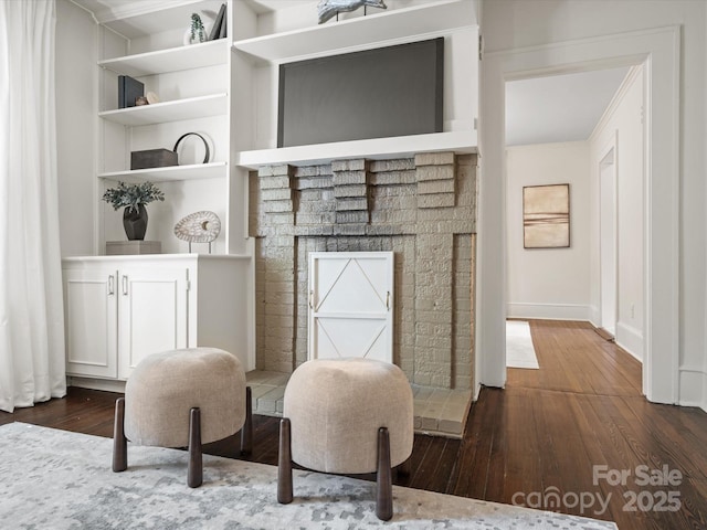 interior space featuring baseboards, ornamental molding, built in shelves, and hardwood / wood-style flooring