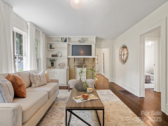 living room with baseboards, dark wood-style floors, and a fireplace