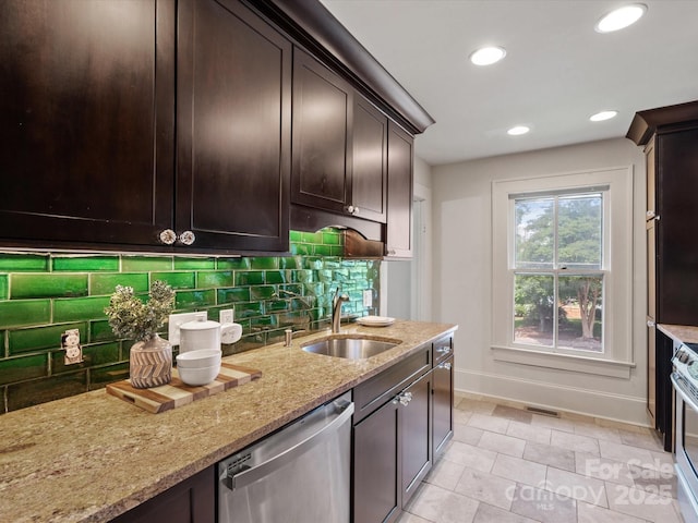 kitchen with dark brown cabinetry, light stone counters, a sink, stainless steel appliances, and baseboards
