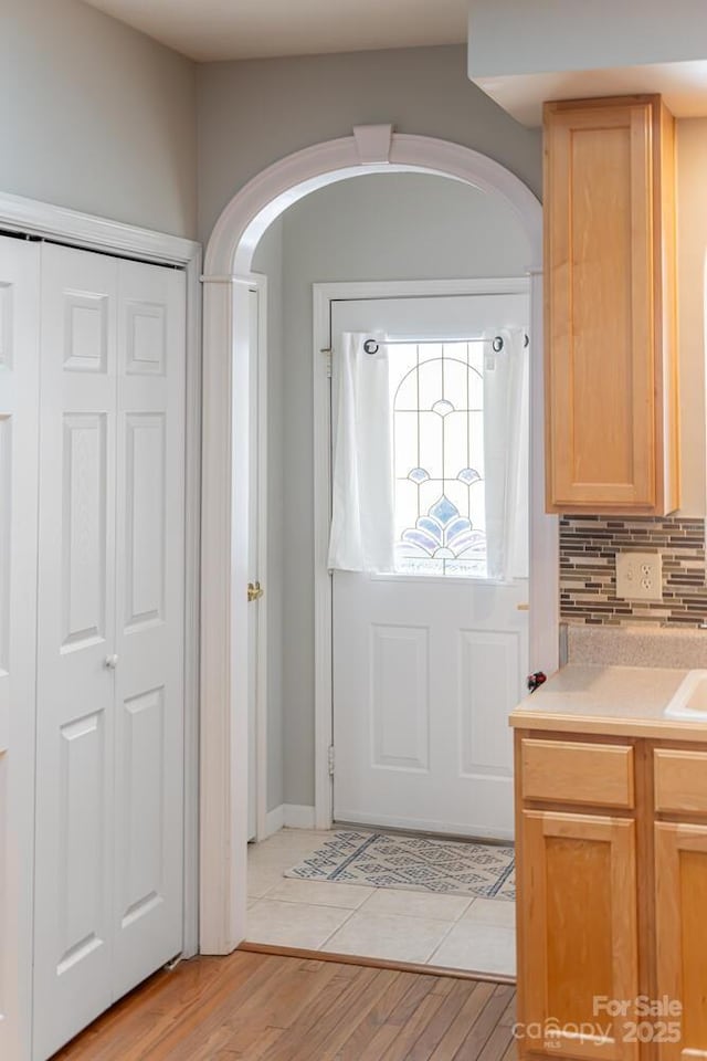 doorway featuring arched walkways and light wood-style floors