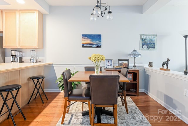 dining area with a chandelier, baseboards, and wood finished floors