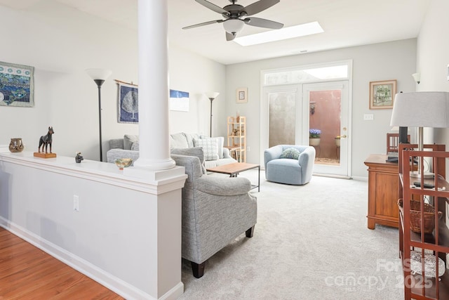 carpeted living room with ornate columns and ceiling fan